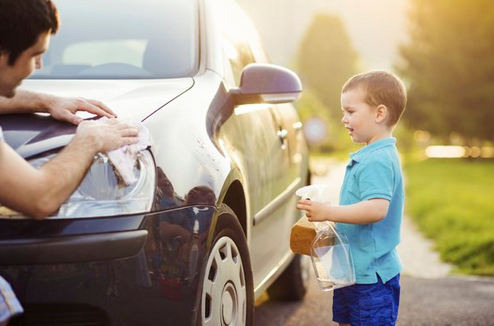 A father and son clean a car.
